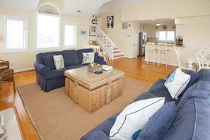 Ein Wohnzimmer mit einer Couch, einem Couchtisch und einer Treppe, die in eine Küche führt.