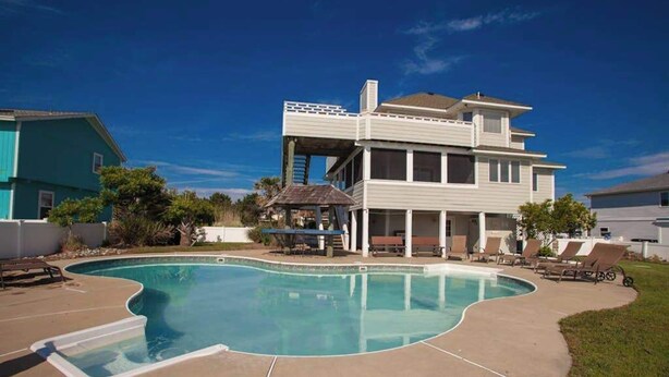 A two-story house with a swimming pool, a covered patio, and a small deck.