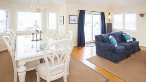 A dining area with a white table and chairs, a blue sofa, and a chandelier.