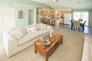 A living room with a sofa, coffee table, and a dining area with chairs and a table. - Canal-front home w/private pool, hot tub, fishing dock, walk to the beach,2 dogs (Virginia Beach)