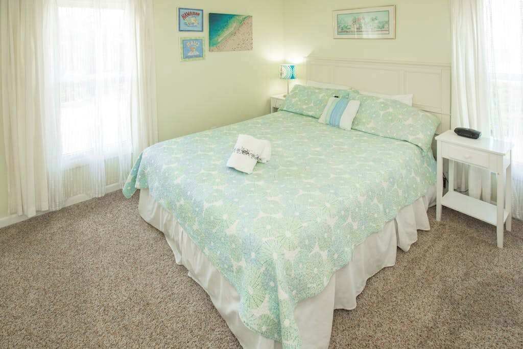 A bedroom with a bed, a bedside table, a lamp, and a window with curtains.