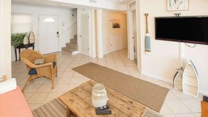 Un salon comprenant un canapé, une table basse, un téléviseur et un escalier menant à une autre pièce.