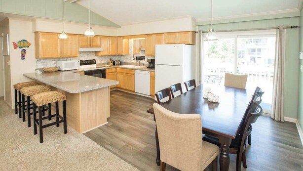 Une cuisine moderne avec des meubles en bois, un îlot central et un coin repas avec des chaises.