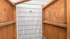 Une structure en bois avec un mur recouvert de bardeaux gris, une porte en métal et une petite fenêtre.