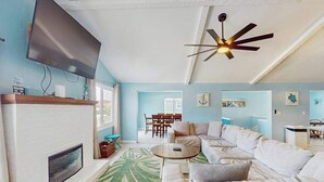 Un salon comprenant un canapé, un téléviseur, une cheminée et un ventilateur de plafond.
