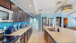 Une cuisine moderne dotée d’un îlot central, d’appareils électroménagers intégrés et d’un mur d’accent bleu.