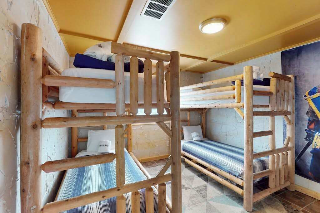 Een kamer met stapelbedden, een muurschildering en een ventilatie rooster.