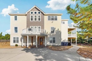 A two-story house with a balcony, a front porch, and a garage. - Dog-friendly home with pool, hot tub, lazy river, splash pad, & game room (Virginia Beach)