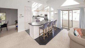 Una cocina amplia con una isla central, taburetes de bar y un comedor con mesa y sillas.