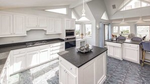 Una cocina amplia con muebles blancos, una isla central y un gran ventanal que proporciona luz natural.