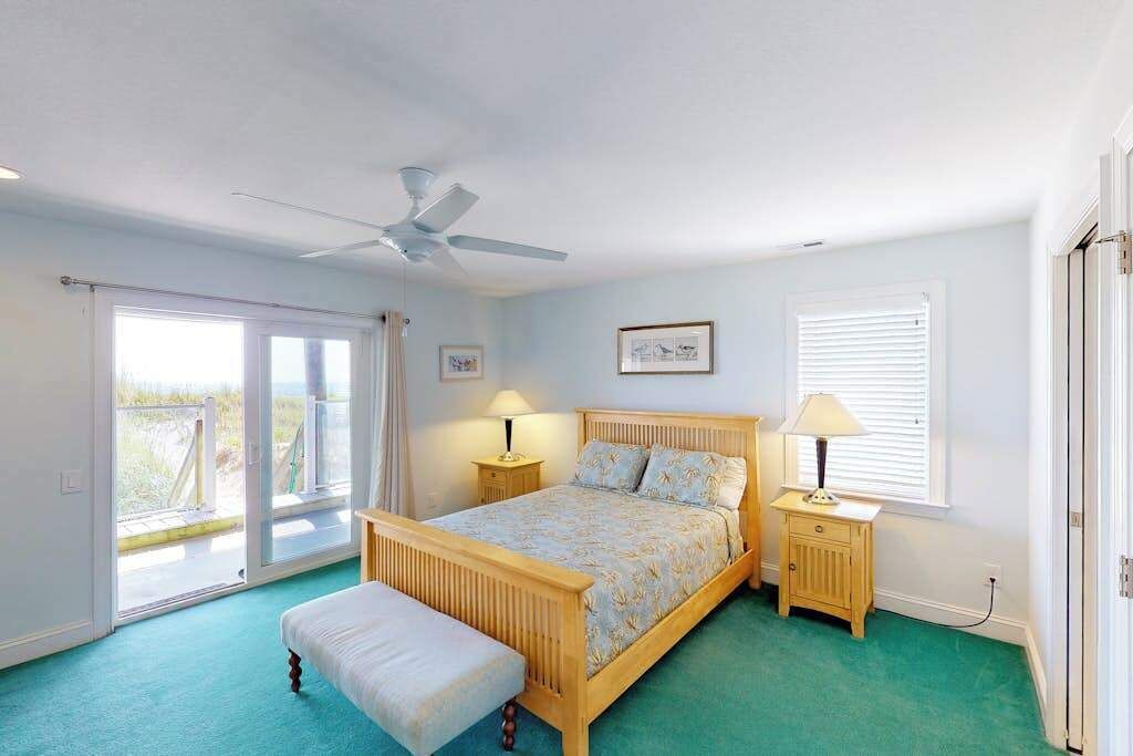 Une chambre à coucher avec un lit, un banc, un ventilateur de plafond, une fenêtre et une porte.