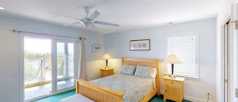 Une chambre à coucher avec un lit, un banc, un ventilateur de plafond, une fenêtre et une porte.
