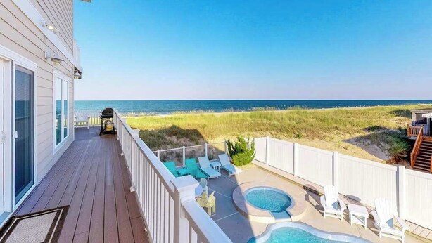 Una terraza con piscina, sillas de descanso y vistas a la playa.