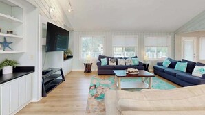 Un salon avec un canapé bleu foncé, un téléviseur à écran plat fixé au mur et une table basse en bois.