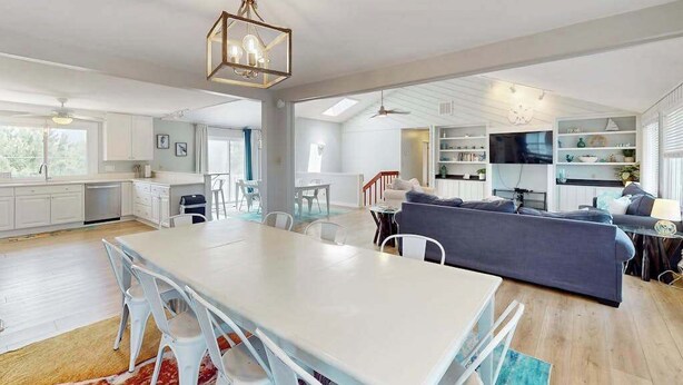 Un vaste espace de vie comprenant une table à manger, des canapés et une cuisine en arrière-plan.