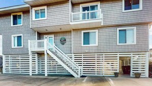 Un immeuble à plusieurs étages doté d’un balcon, d’un escalier et d’une entrée fermée par un portail.