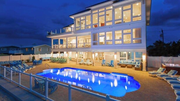 A two-story hotel with a swimming pool, outdoor seating, and a well-lit facade.