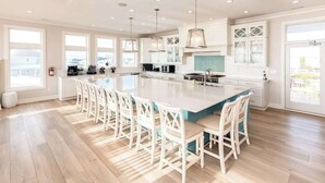 A spacious kitchen with a large island, white cabinetry, and pendant lighting.