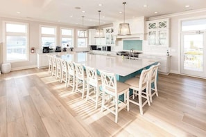 A spacious kitchen with a large island, white cabinetry, and pendant lighting.