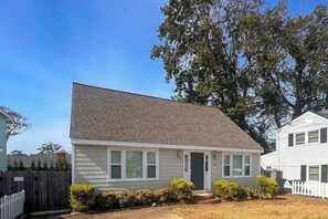 A single-story house with a gabled roof, a front porch, and a small front yard with shrubs. - Sweet Home Near Croatan Beach & Boardwalk with Deck, WiFi, Bikes - 2 Dogs OK (Virginia Beach)