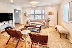 A living room with a sofa, coffee table, chairs, a TV, and a lamp. - Sweet Home Near Croatan Beach & Boardwalk with Deck, WiFi, Bikes - 2 Dogs OK (Virginia Beach)