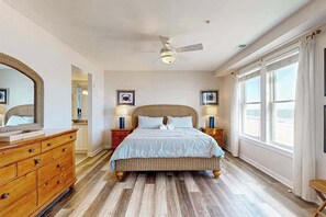 Ein Schlafzimmer mit einem Bett, einem Holzschrank, Nachttischen, einem Deckenventilator und gerahmten Bildern an der Wand.