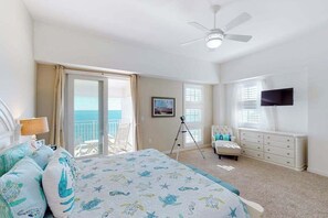 A bedroom with a bed, a TV, a balcony, and a ceiling fan. - Oceanfront, 2-story penthouse with 3 balconies, 3 pools & 2 gyms (Virginia Beach)