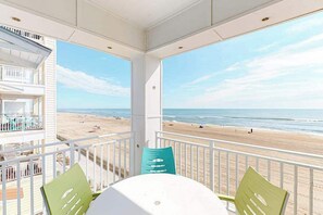 A balcony with a view of the beach and ocean. - Beachfront condo with balcony, W/D, 3 outdoor pools, gym & AC (Virginia Beach)