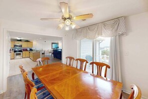 A dining area with a wooden table and chairs, a ceiling fan, and a view of the kitchen and living room. - Beautiful home close to the Atlantic w/shared pool, private washer/dryer, WiFi (Virginia Beach)