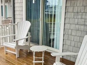 A covered deck with white Adirondack chairs and a small round table. - 1st-floor Seaside condo 1 block from beach with pool & private deck (Virginia Beach)