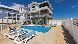 A two-story building with a swimming pool, outdoor seating, and a fenced area. - Inviting oceanfront home with amazing views, private pool & deck (Virginia Beach)