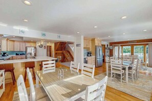 A spacious kitchen with wooden cabinets, a central island, and a dining area with white chairs. - Lovely, contemporary home w/private pool/hot tub, easy beach access, central AC (Virginia Beach)