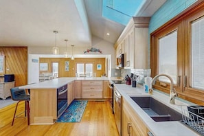 A modern kitchen with wooden cabinets, a central island, a large sink, and pendant lighting. - Lovely, contemporary home w/private pool/hot tub, easy beach access, central AC (Virginia Beach)