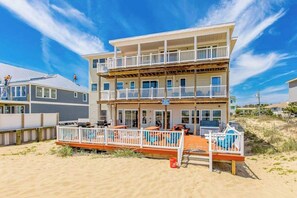 Ein mehrgeschossiges Gebäude mit Balkonen, einer Terrasse und Blick auf den Strand.