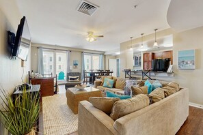A living room with a sofa, a coffee table, and a television. - Newly Refreshed 3BR Bay & Ocean-View Condo -Balcony, Pool & Gym (Virginia Beach)