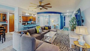 A spacious living room with a sofa, coffee table, and a ceiling fan. - 1st-floor condo with views of Back Bay, balcony, AC, outdoor pool & gym (Virginia Beach)