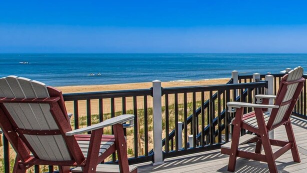 Une terrasse avec deux fauteuils Adirondack donnant sur une plage.