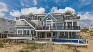 Une maison à deux étages située en bord de mer, dotée d’un balcon, d’un escalier et d’une piscine.