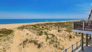 Une vue sur la plage avec une terrasse en bois et une rambarde.