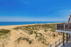 Une vue sur la plage avec une terrasse en bois et une rambarde.