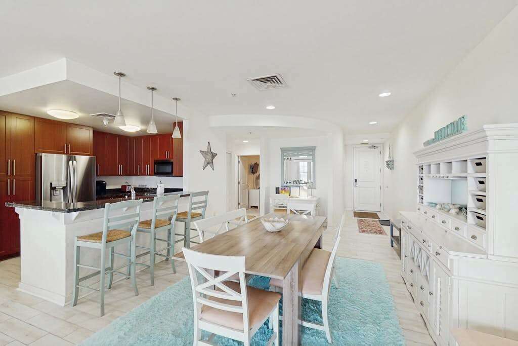 Una cocina moderna con una isla central, armarios de madera e iluminación colgante.