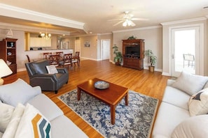 A spacious living room with a sofa, a coffee table, and a television. - Southside condo with ocean view, easy beach access, fast WiFi & on-site pool/gym (Virginia Beach)