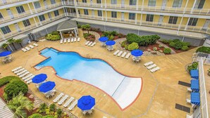 Ein Hotel mit Swimmingpool, Liegestühlen und Sonnenschirmen.