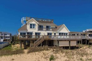 A beachfront house with a balcony, a staircase, and a deck. - Oceanfront home with private pool, crow's nest deck, game room & fireplace (Virginia Beach)