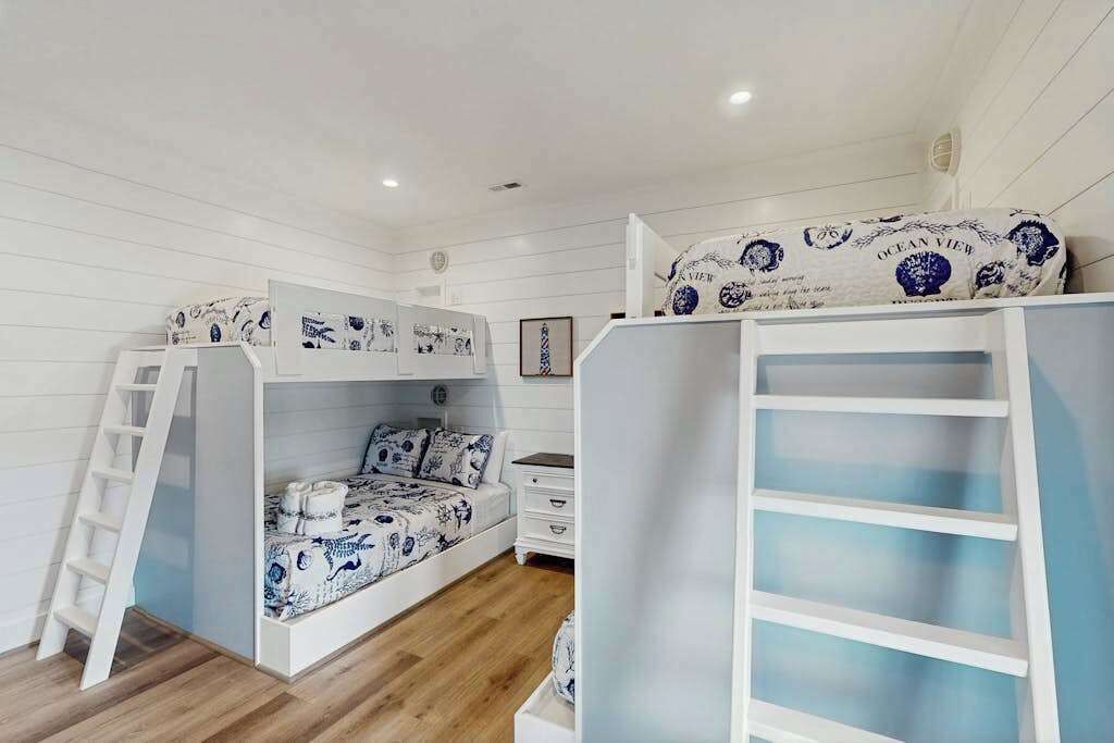 Une chambre avec des lits superposés, une échelle, une commode et un tableau encadré accroché au mur.