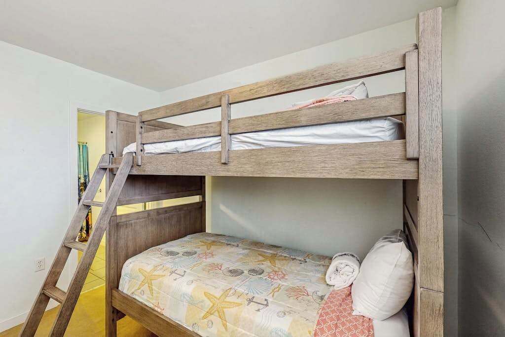 A bunk bed with a ladder, a patterned bedspread, and pillows.