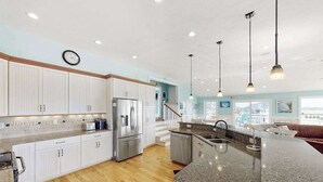 A modern kitchen with white cabinets, stainless steel appliances, and a granite countertop. - Fully-equipped canal-front home w/private outdoor pool, bay, dock, and views (Virginia Beach)