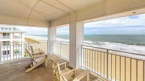 Ein Balkon mit Holzstühlen und Blick auf den Strand.
