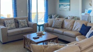 Ein Wohnzimmer mit zwei Sofas, einem Couchtisch und Blick ins Freie.