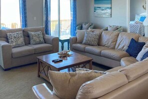 A living room with two sofas, a coffee table, and a view of the outdoors. - Oceanfront home with beach access, huge decks & pool table - great for groups (Virginia Beach)